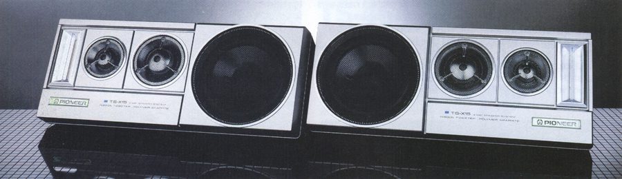 Alt text: Vintage Pioneer TS-X15 car stereo speakers with distinctive circular design and silver casing, placed on a reflective surface.