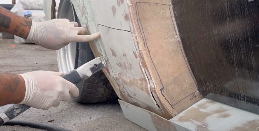 Mechanic using tools to repair and customize a car's fender for better performance and appearance in a workshop.
