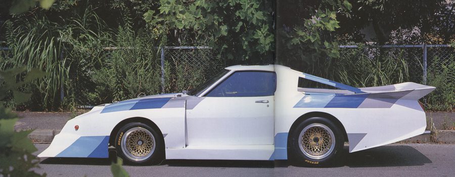 Side view of a modified white and blue Nissan Sunny B110 race car with aerodynamic body kit and large rear wing.