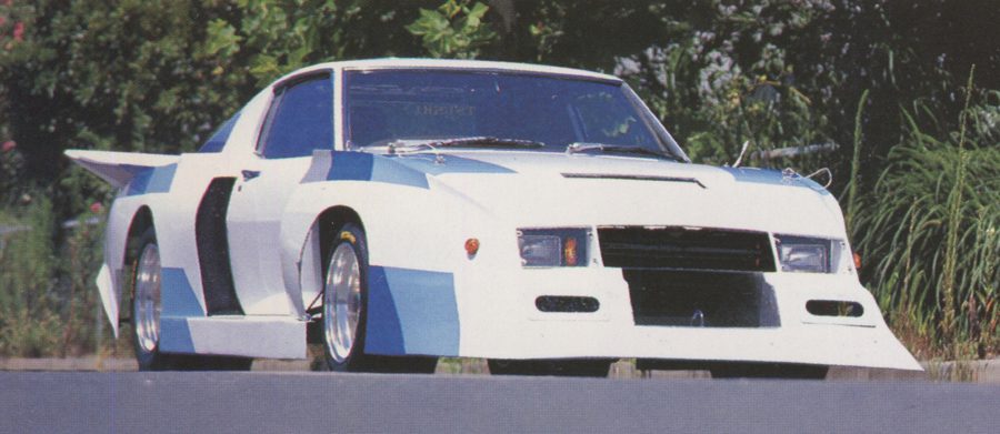Japanese modified car with a custom wide body kit and bold blue and white paint job parked on a sunny day.