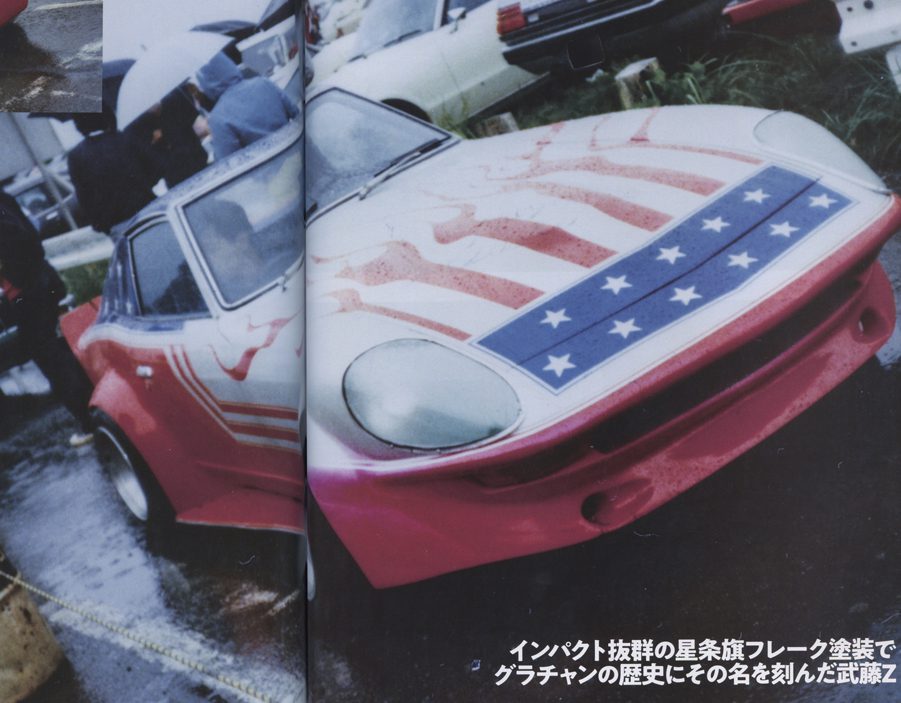 Colorful custom sports car with an American flag-themed paint job in a rainy outdoor event. Japanese text on the image.