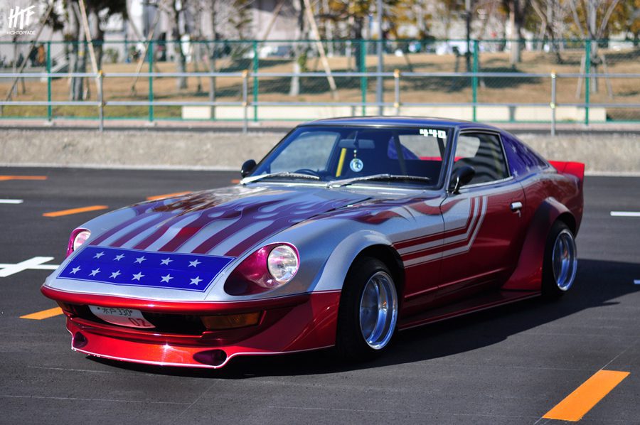 Classic car with an American flag-themed paint job parked in a lot with Japanese license plate 399.