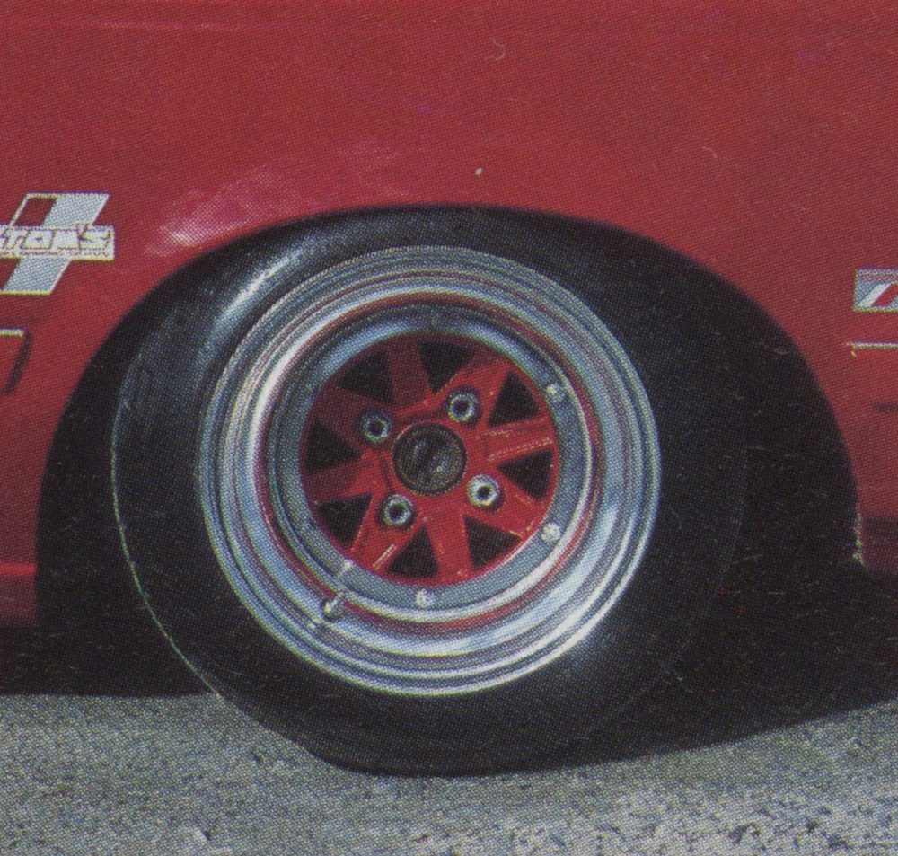 Close-up of a red car's custom wheel featuring a red star-shaped rim with silver outline, set against a matching red body.