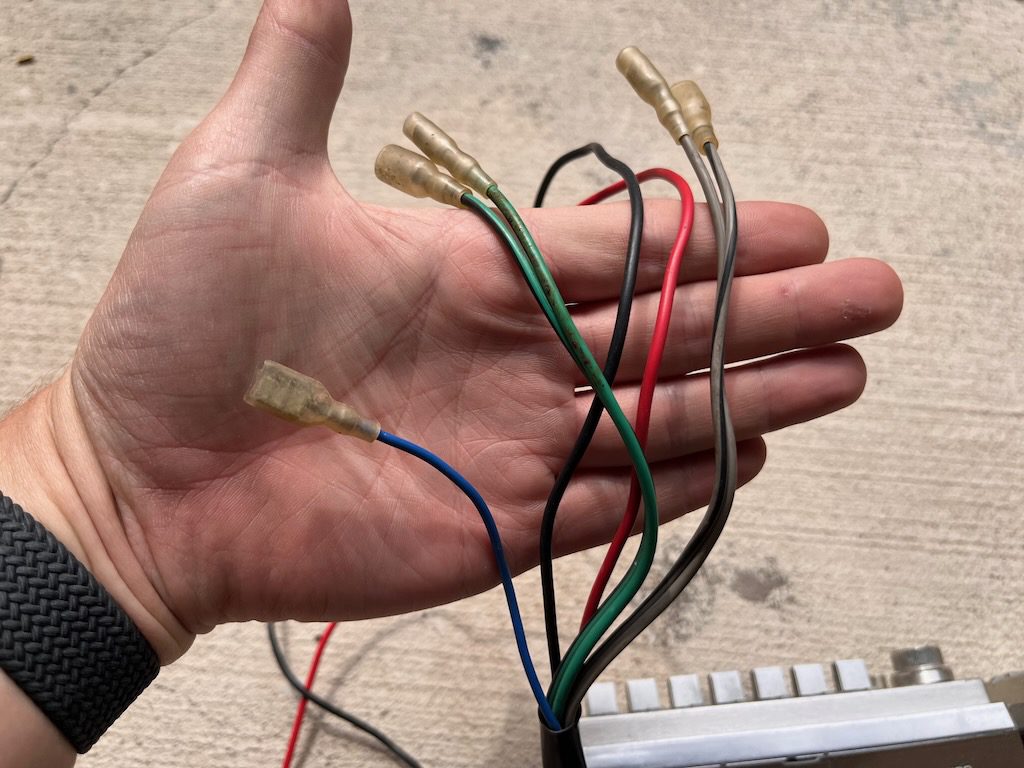 A hand displaying multiple colored electrical wires with connectors, indicating installation or repair work.