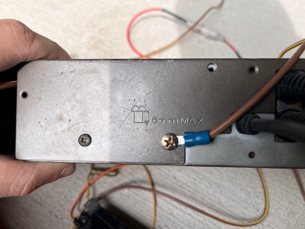Close-up of a metal component with wires attached, marked 6mm MAX, held by a hand against a light background.
