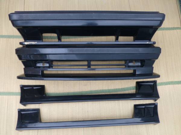 Four black car bumpers placed on a tatami mat, arranged in a neat horizontal layout.