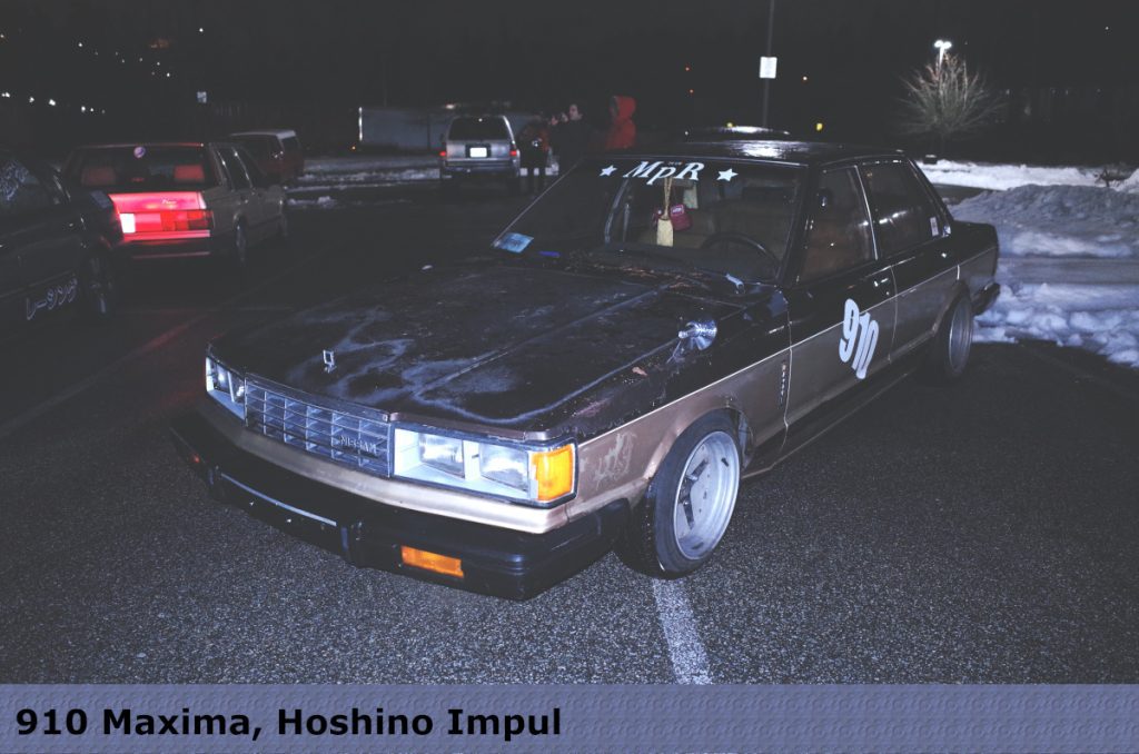 Classic 910 Maxima parked at night, featuring Hoshino Impul wheels. Japan-inspired design visible on nearby car.