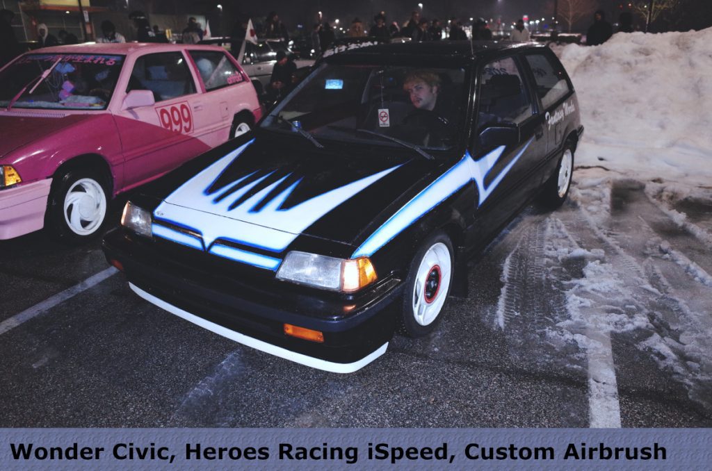 Two custom Japanese cars at a night event: one pink with 999 number, one black with blue airbrush, snow in the background.