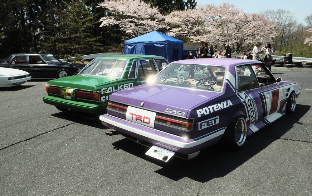 Modified Toyota GX61 and GX71 cars at a nonsuri event with cherry blossoms in the background.