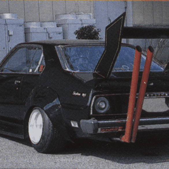 Modified classic black car with large rear wing and dual exhaust pipes for a unique street racing style.