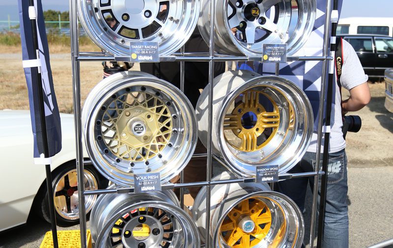 Display of polished car rims including Target Racing, Longchamp XR-4, Volk Mesh, and Shadow Spoke at a car event.