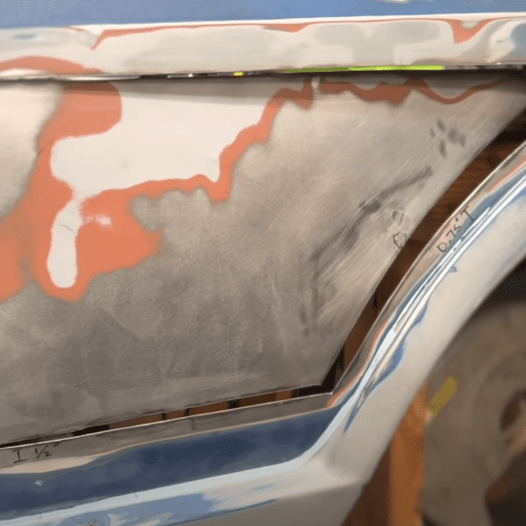 Car bodywork repair in progress, features rust removal and patch panel fitting with measurements marked in inches.