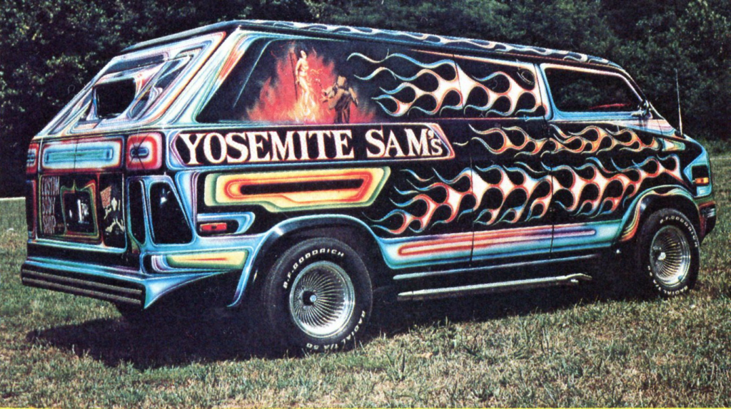 Colorful custom-painted van featuring flames, murals, and Yosemite Sam's text on the side, parked on grass.