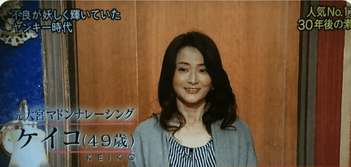 A smiling woman named Keiko, 49 years old, stands in front of a wooden background with Japanese text on the screen.