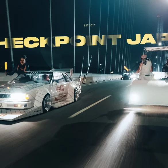 Vintage cars on a Japanese bridge at night with the text Checkpoint Japan.