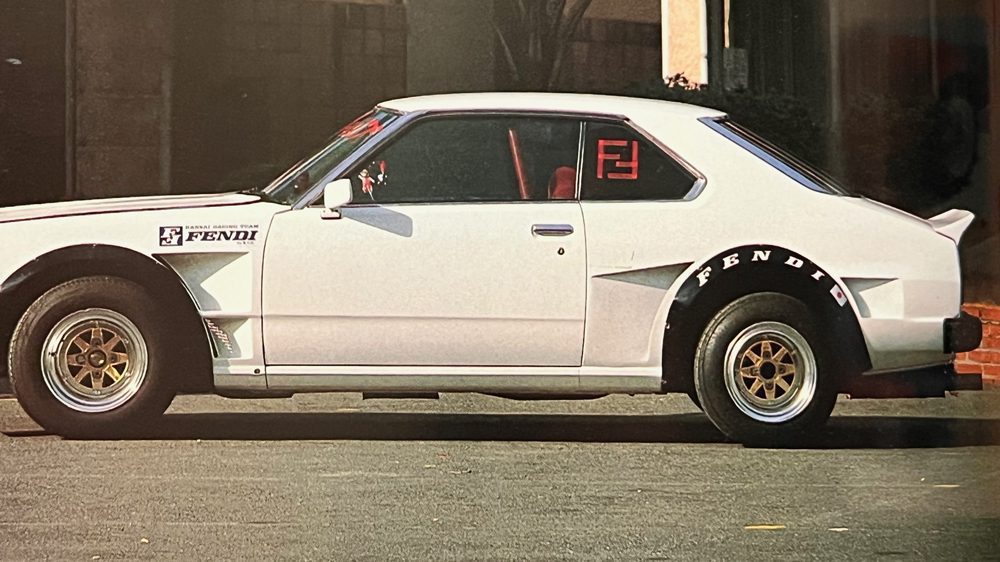 Customized white sports car with Fendi decals and gold wheels, parked on a street in Japan.