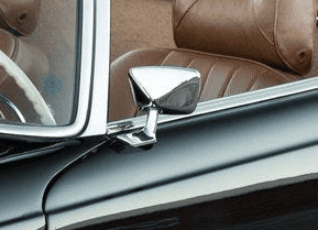 Close-up of vintage car interior with leather seats and chrome side mirror for a classic automotive look.