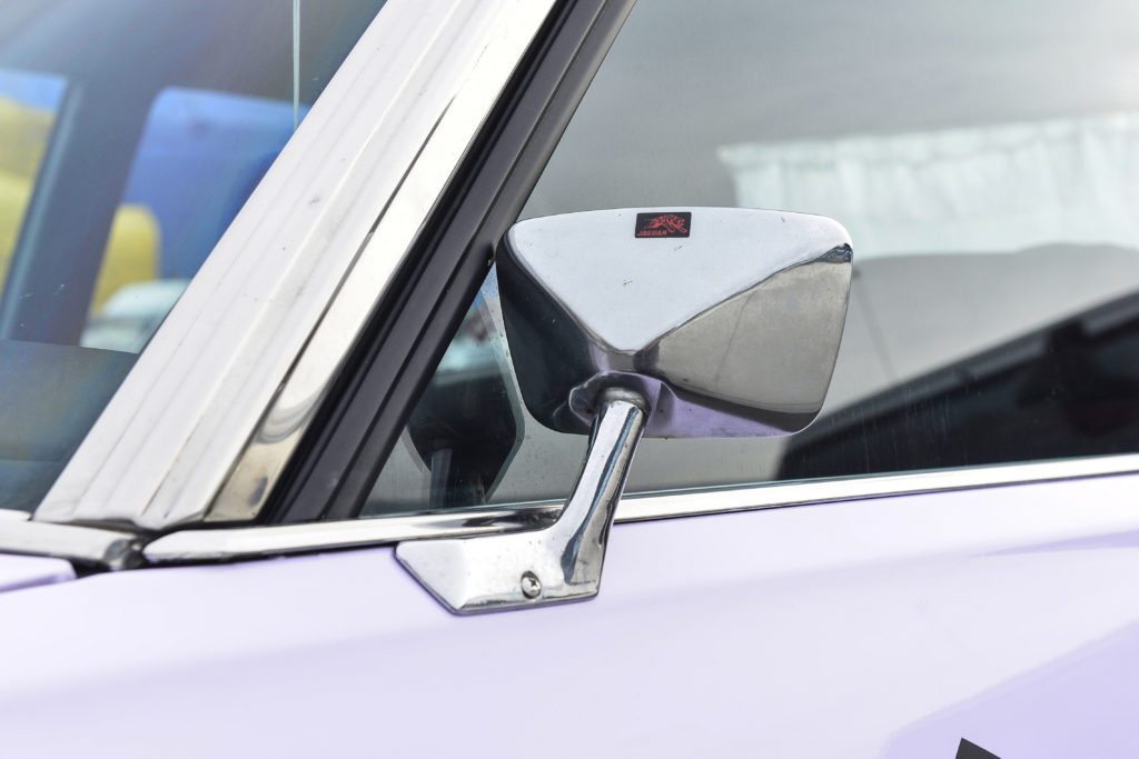 Vintage car's chrome side mirror with Japanese sticker reading 日本グッドイヤーポールブレーキ, translating to Japan Goodyear Pole Brake.