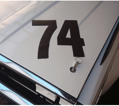 Alt text: Close-up of a car hood with the number 74 and a keychain lying on it
