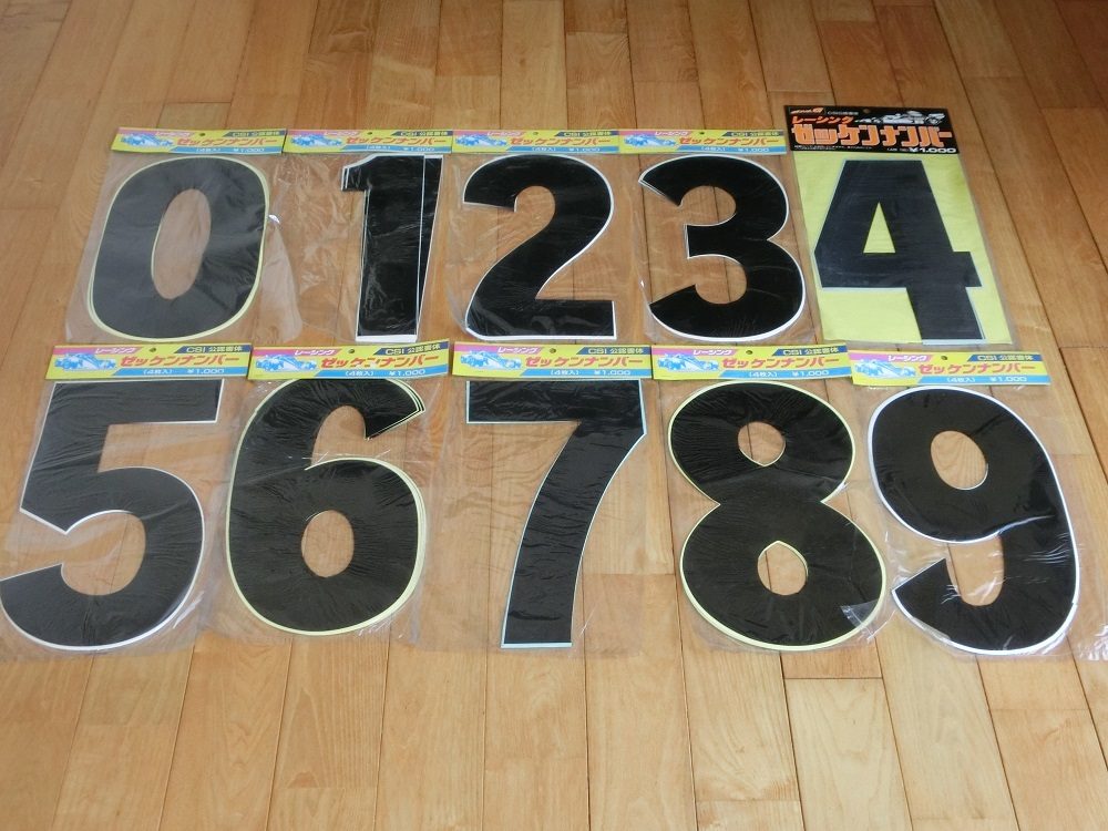 Large black adhesive numbers 0 to 9 in packaging on wooden floor, with Japanese labels translated to ‘Set Numbers’