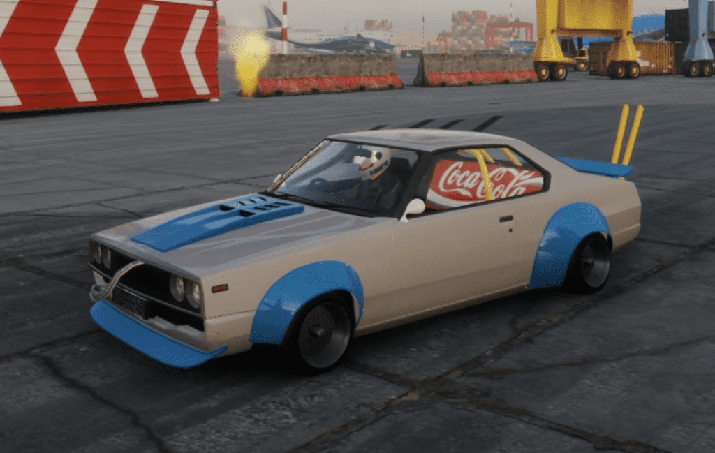 Modified vintage car with Coca-Cola banner on the side at an industrial area, painted in blue and white.