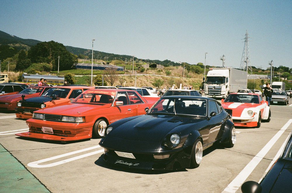 Vintage sports cars parked at an outdoor car meet on a sunny day.