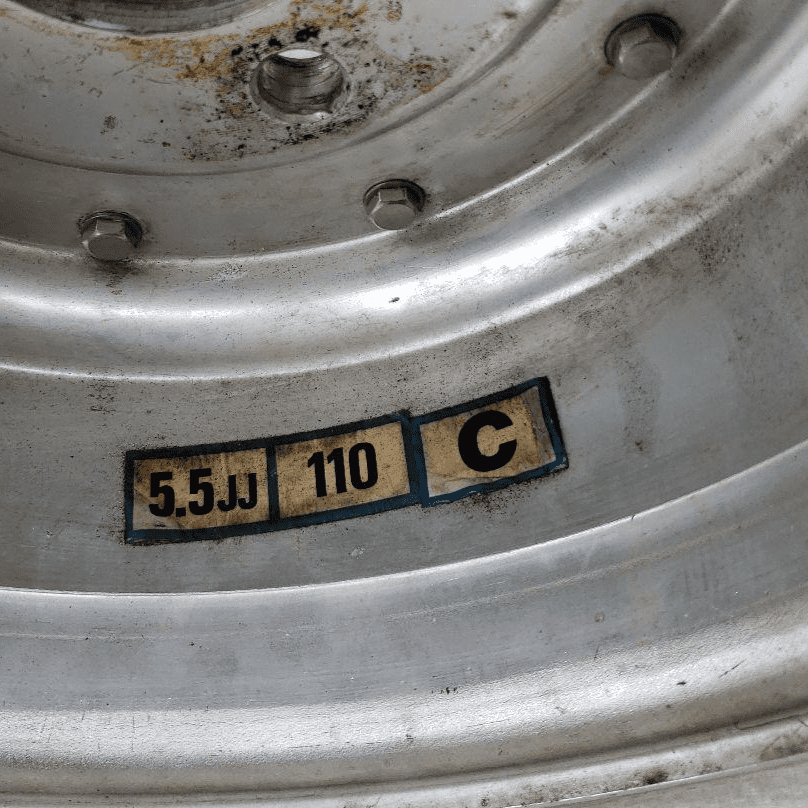 Close-up of a metal wheel rim with markings 5.5JJ, 110, and C in a vintage industrial style.