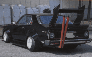 Modified classic black car with large rear wing and dual exhaust pipes for a unique street racing style.