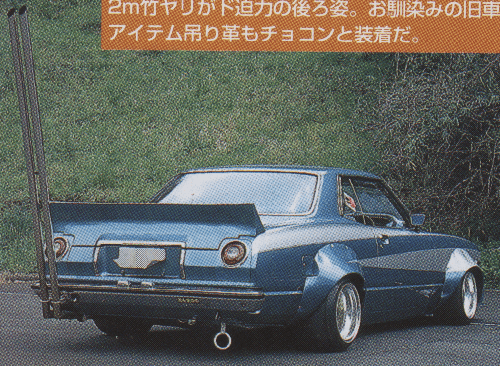 Vintage car with tall exhaust pipes in a grassy area, showcasing retro automotive style and design.