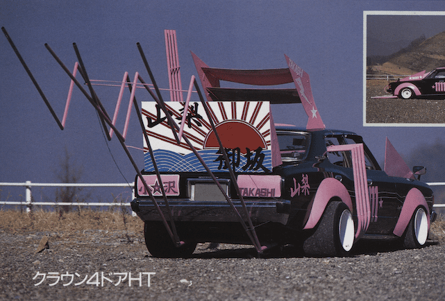 Customized Japanese car with vibrant pink accents and unique rear design in a scenic outdoor setting.